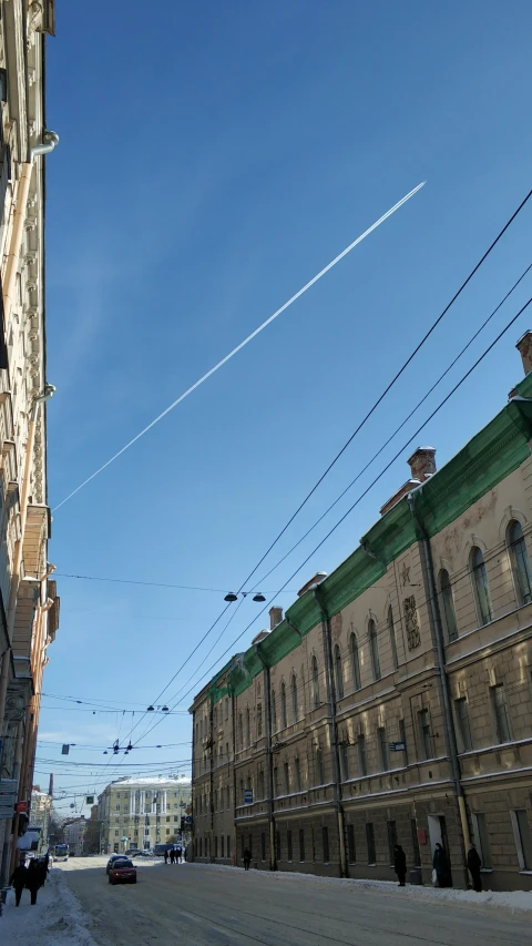 an airplane is flying over a street by buildings