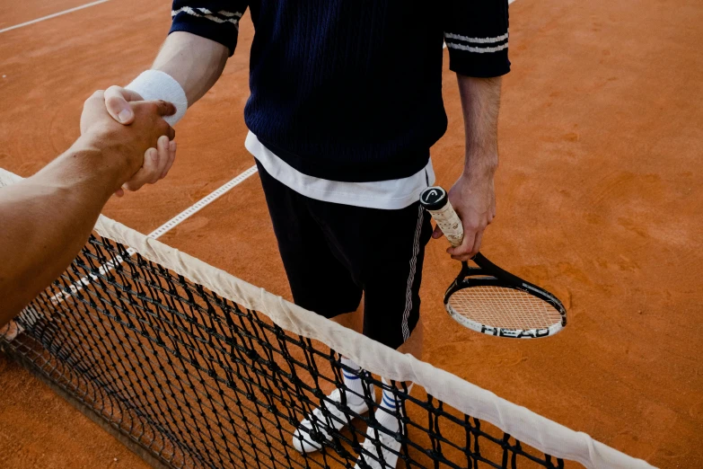 a person is shaking another person's hand on the court