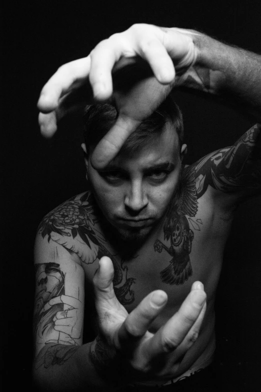 a man with tattoos covers his eyes and hands
