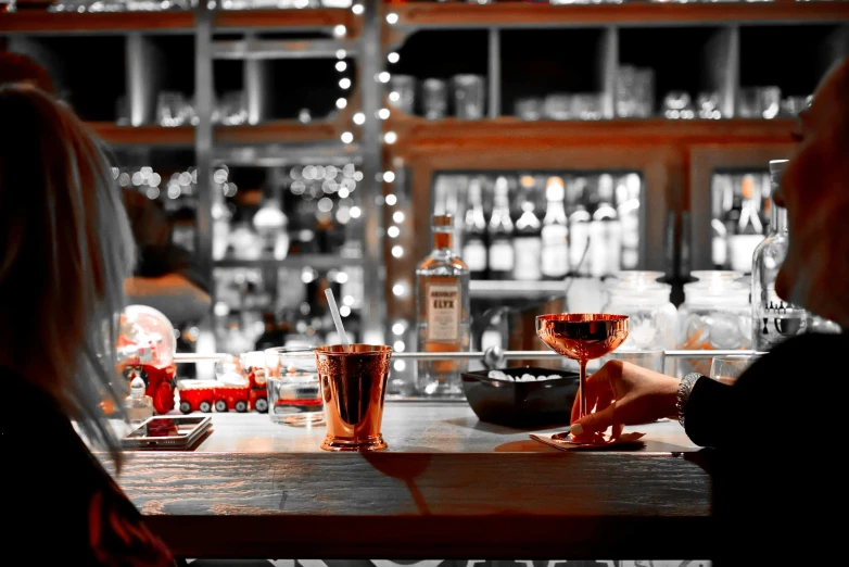 two people in a bar drinking glasses and looking at the bar