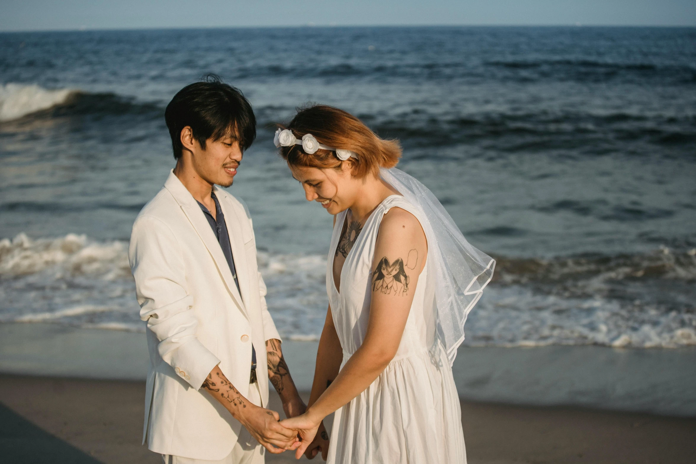 a bride and groom hold hands near the ocean