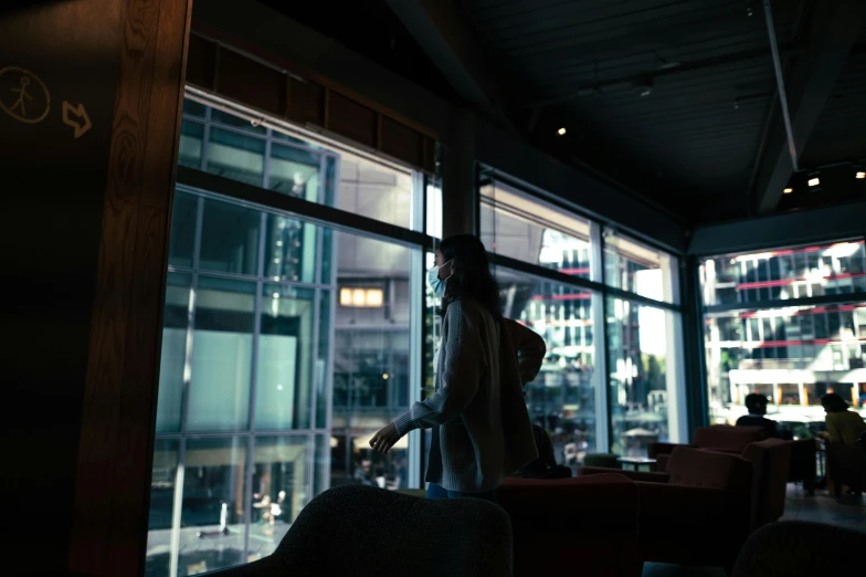 a woman is standing at the window of a dimly lit restaurant