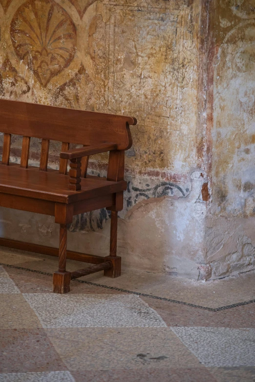 a wooden bench in front of a wall with graffiti