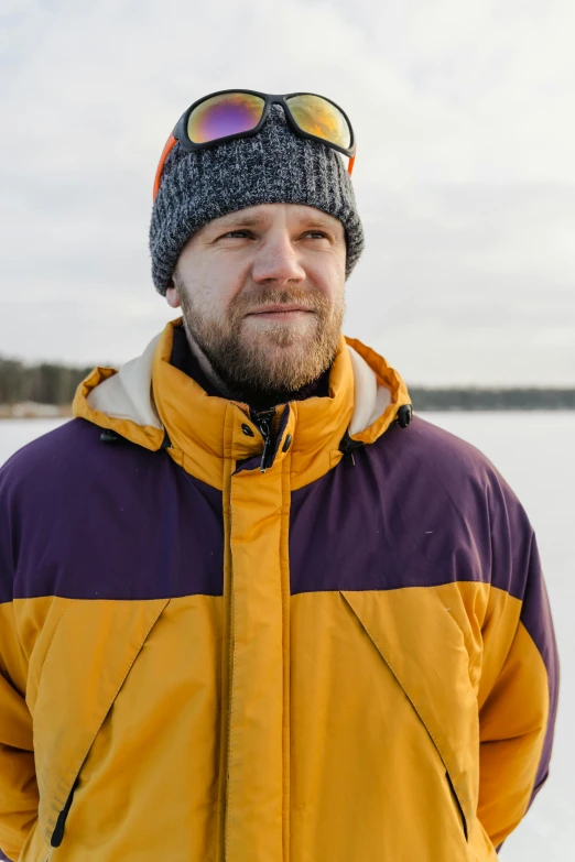 a man in a yellow coat and hat on some snow