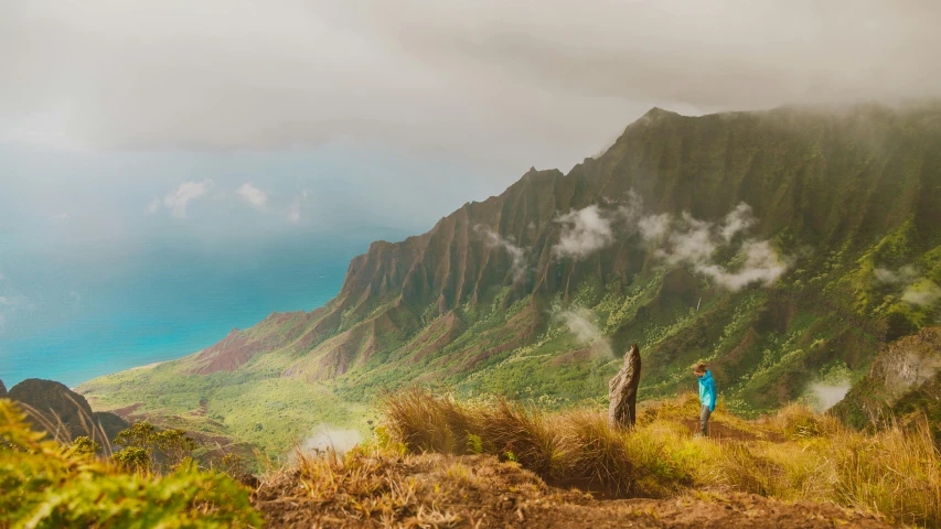 two people standing on the edge of a mountain overlooking the clouds