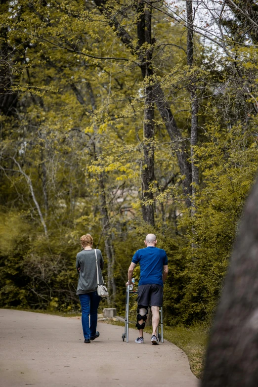 an older couple with walkers are walking in the park