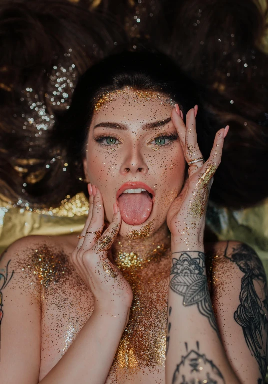 a woman with gold glitter on her body and hands with a hat on top