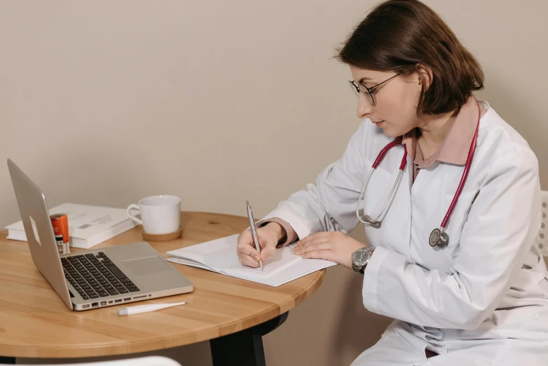 a nurse writing on her paper by her laptop