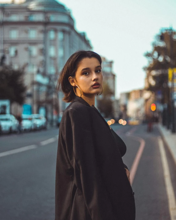 the woman is standing near a street with a tall building