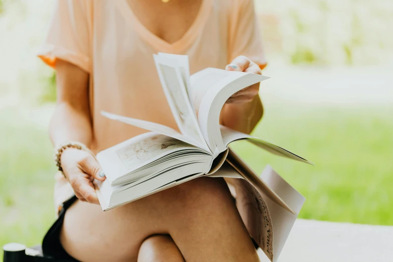 a person is sitting down reading an open book