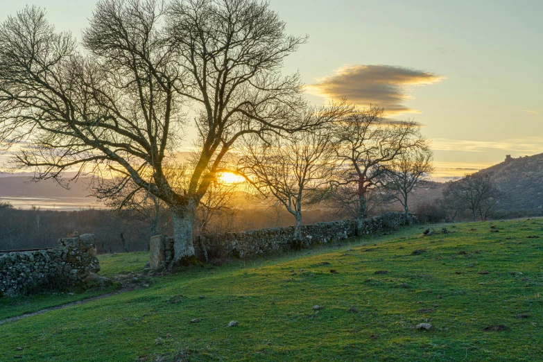 the sun sets over an outcropped stone wall