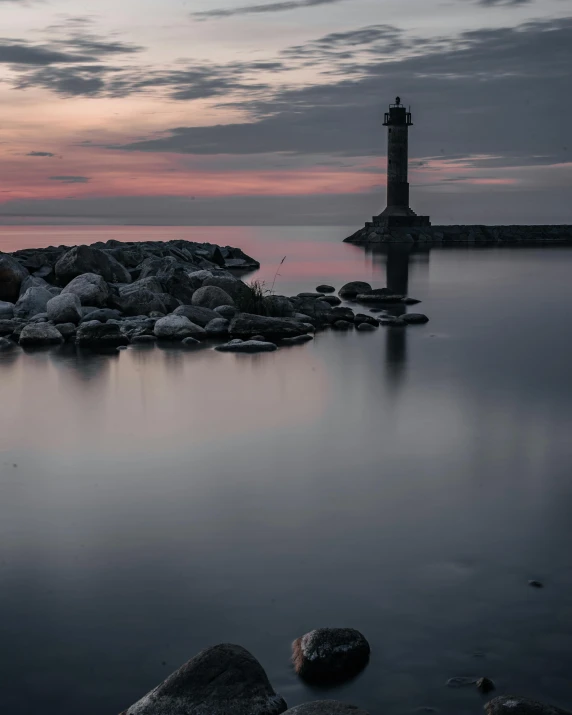 a small lighthouse near the ocean and it is on some rocks