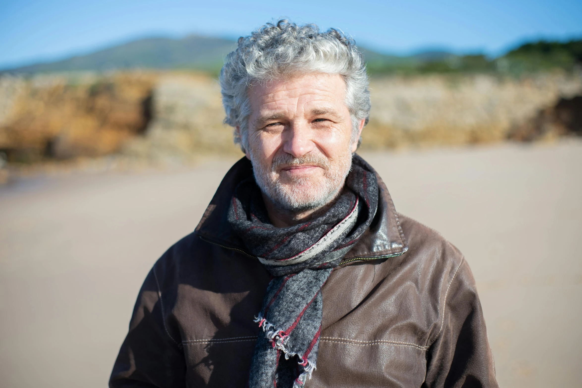 a man standing on a beach wearing a scarf