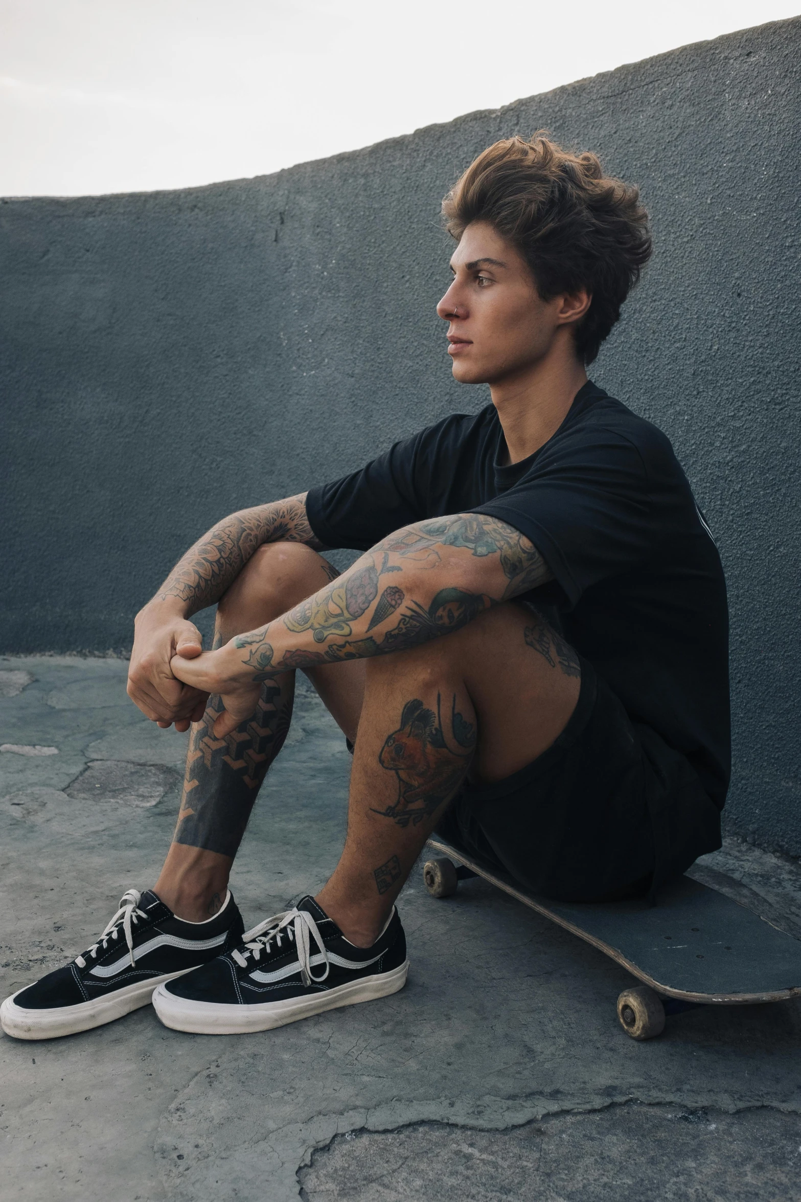 a man sits on the ground next to his skateboard