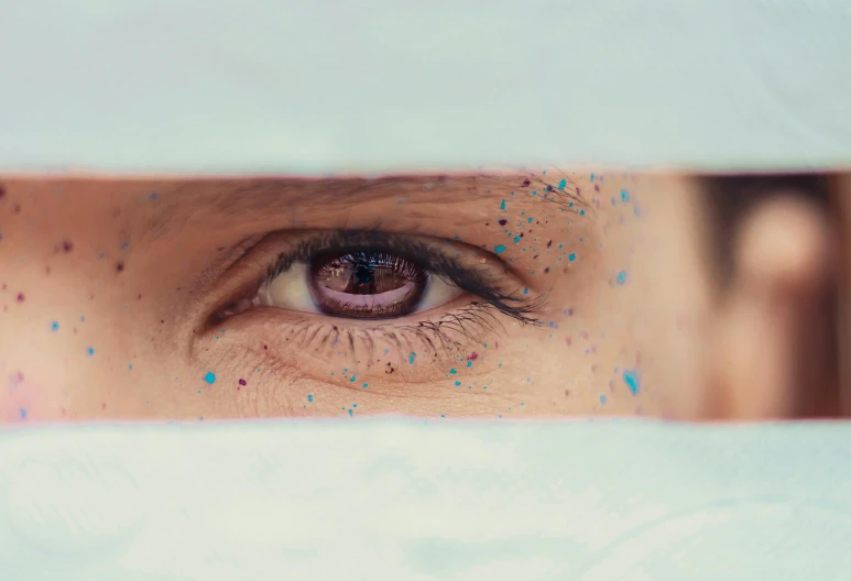 a person's eye peeks out from under the sheets