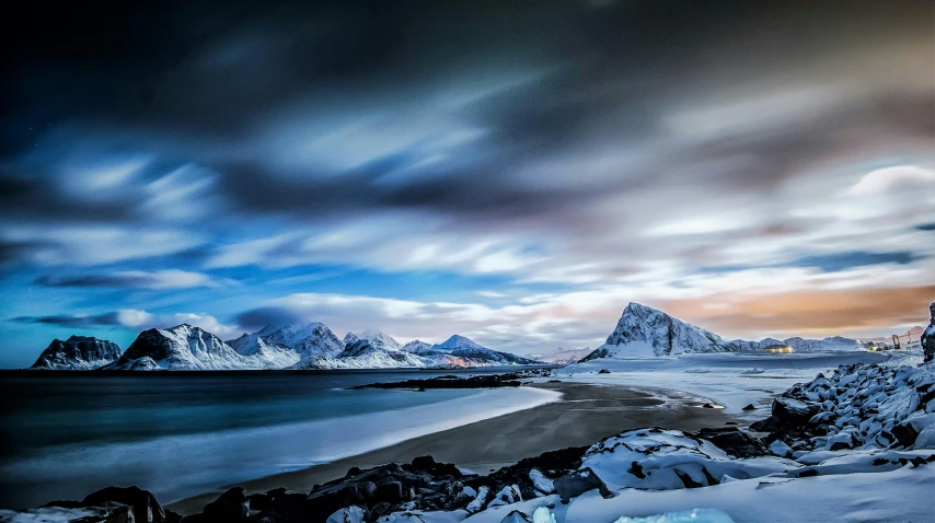 a snow covered beach with mountains in the background