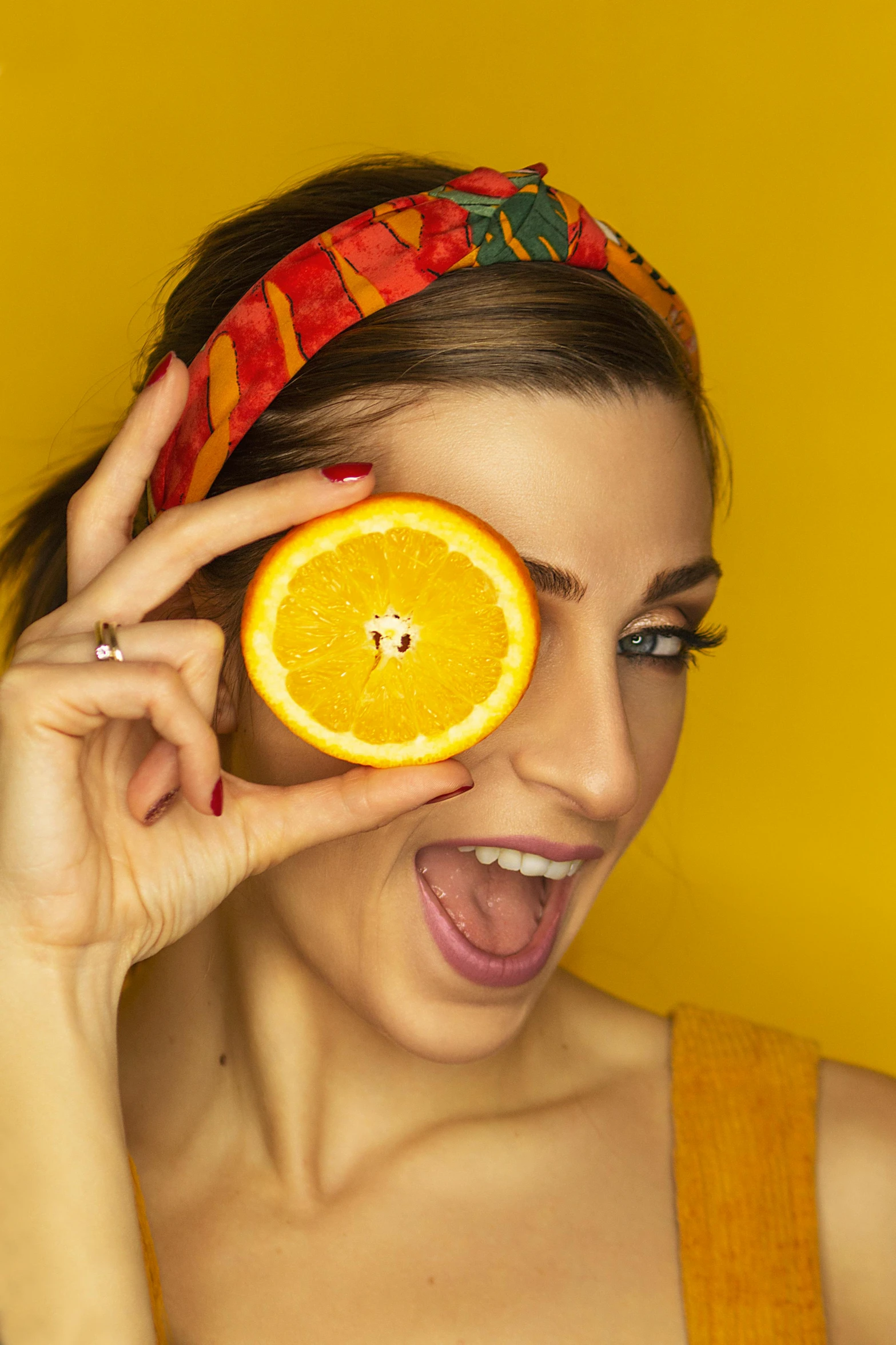 a woman is holding an orange up to her eye