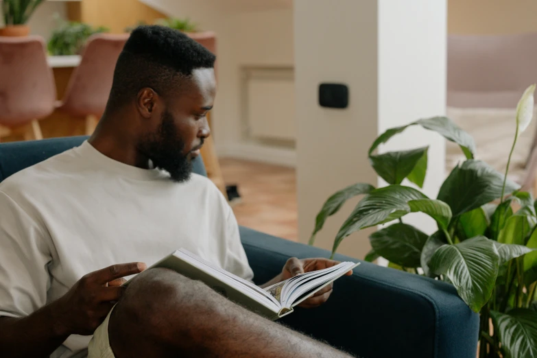 a man sitting on a blue couch reading a book