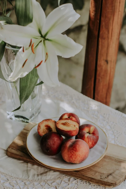 fresh fruit is on a plate next to a glass vase