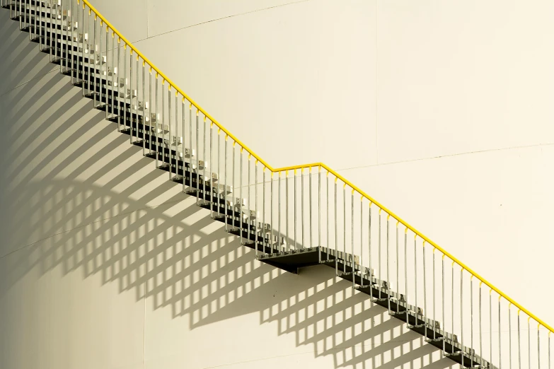 some stairs with yellow rails that are next to a wall