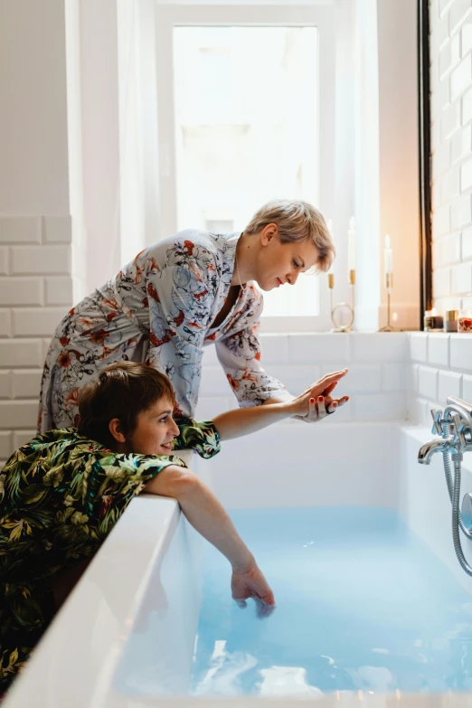 woman and child in bathtub with water streaming from the tub