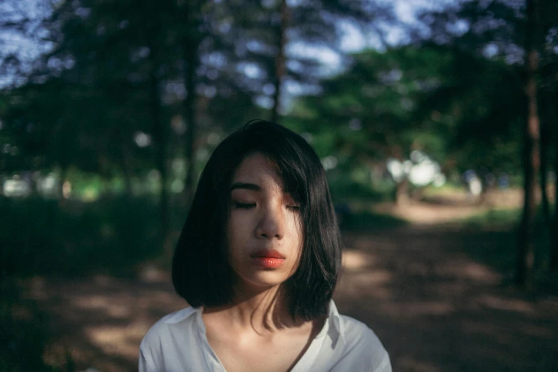 a woman is looking to her right in the woods