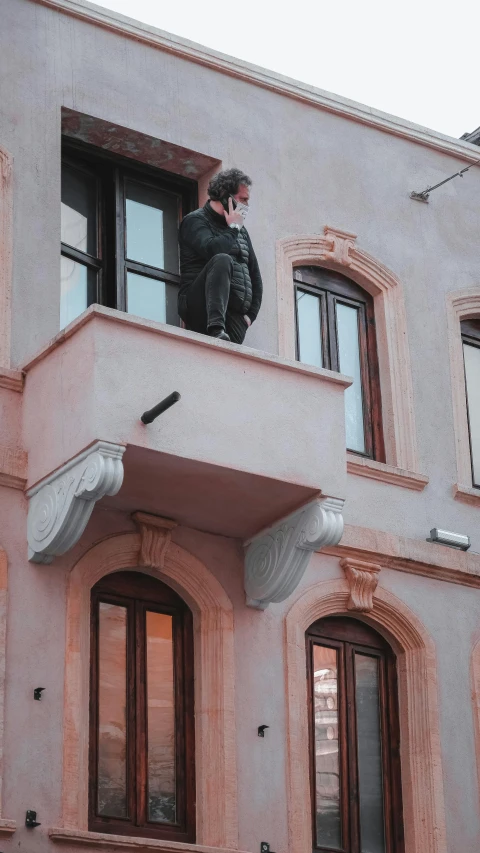 a man standing on the outside balcony of an apartment building