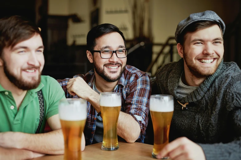 three men smiling at the camera while drinking beer