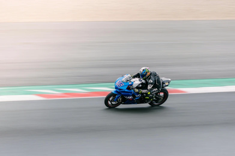 a man driving a motorcycle around a bend while another person races the bike behind him