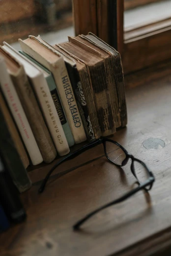 glasses next to books that are on a table