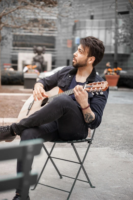 a man sitting on a chair playing an acoustic guitar