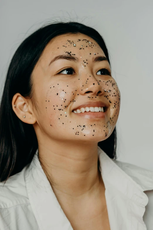 young woman smiling with black dot on her face