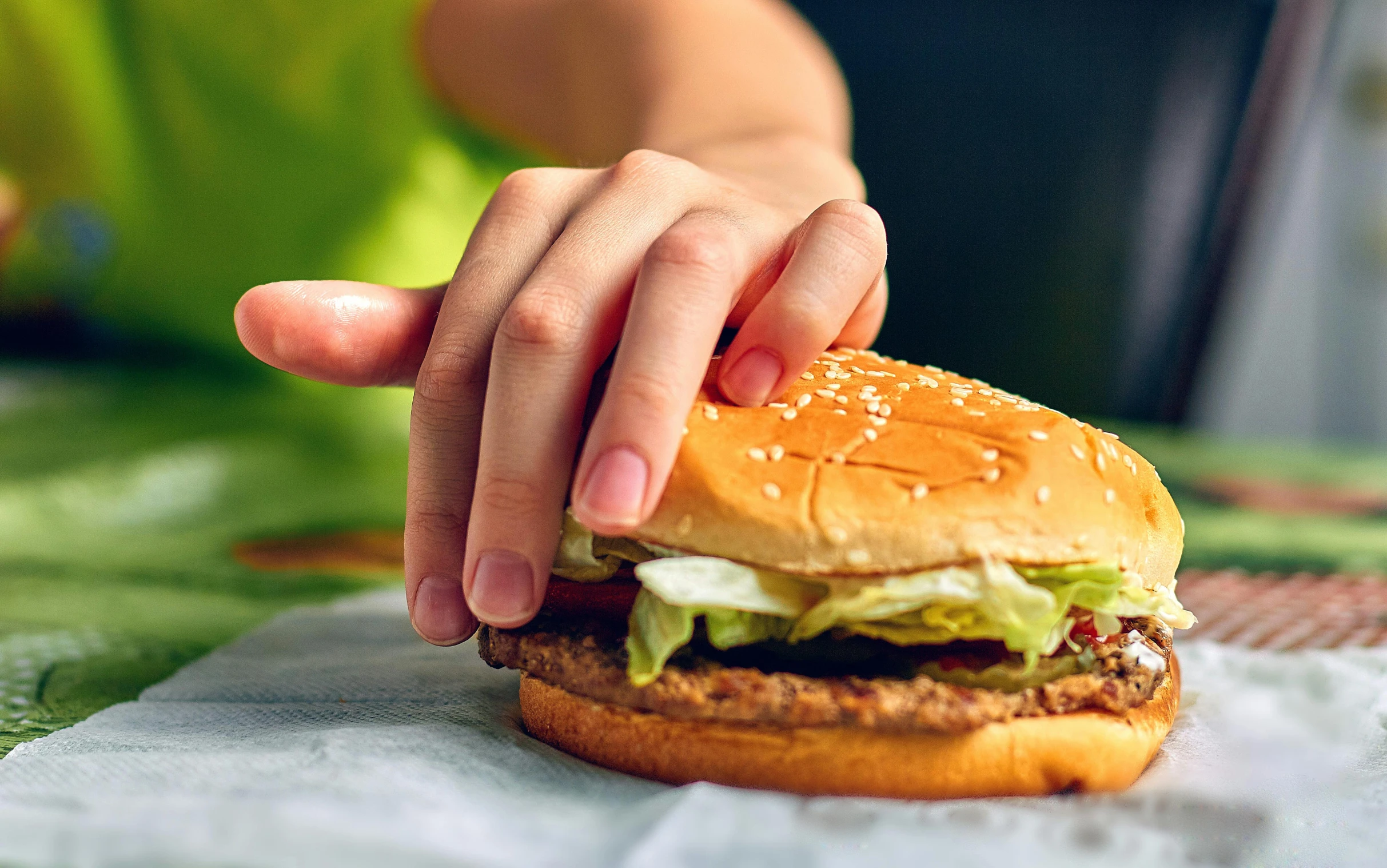 a hand is on top of a hamburger