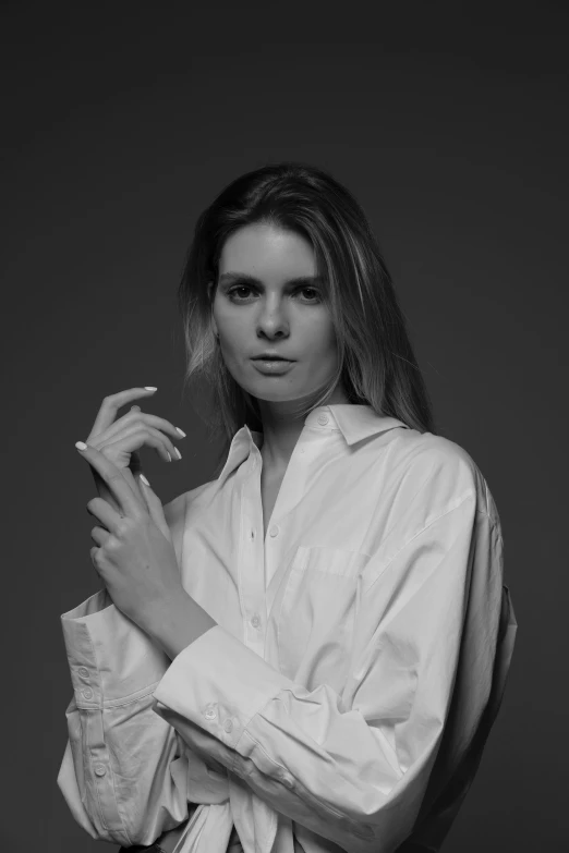 a woman poses in a white shirt with a cigarette