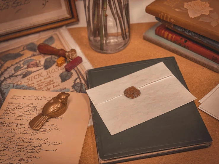 a desk with envelope, gold bird brooch and other letters