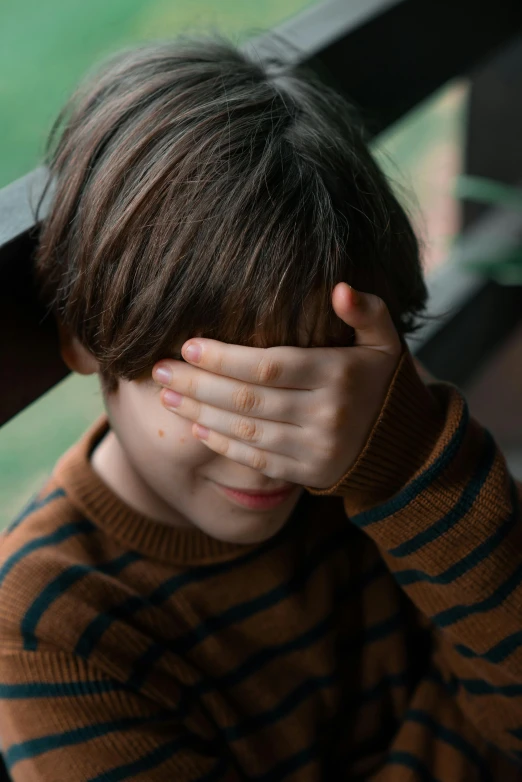 a boy covering his face from the sun with his hands