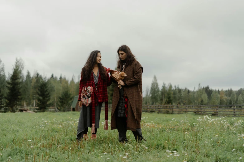 two people with long hair and a goat on the grass