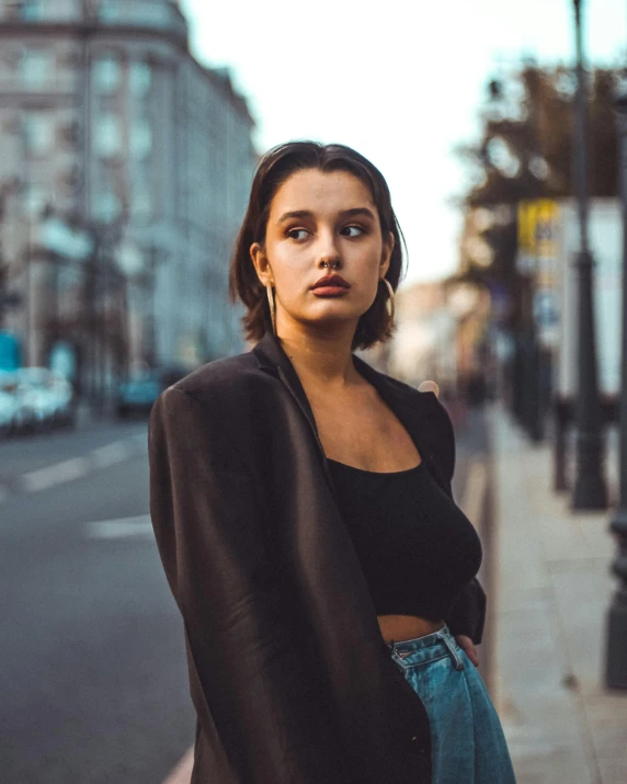 a woman is looking at the camera while standing on the sidewalk