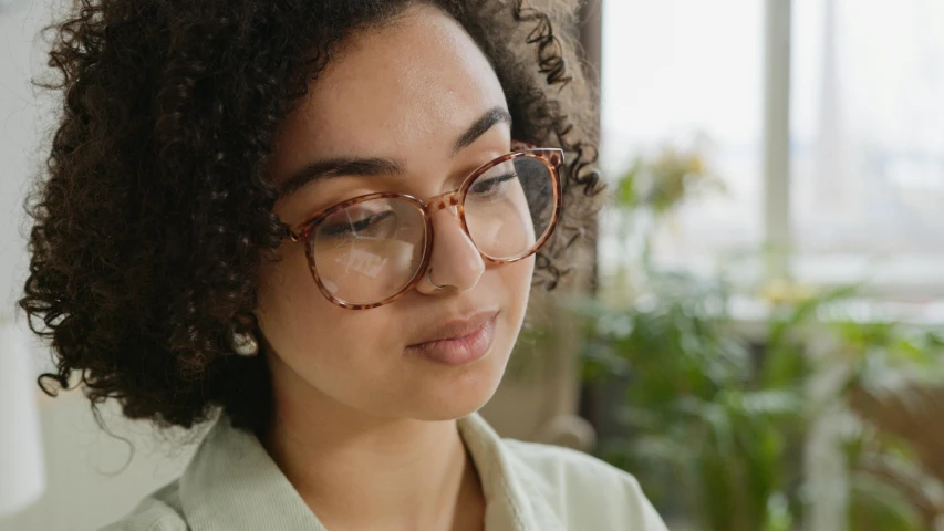 the woman wears glasses and looks off into the distance