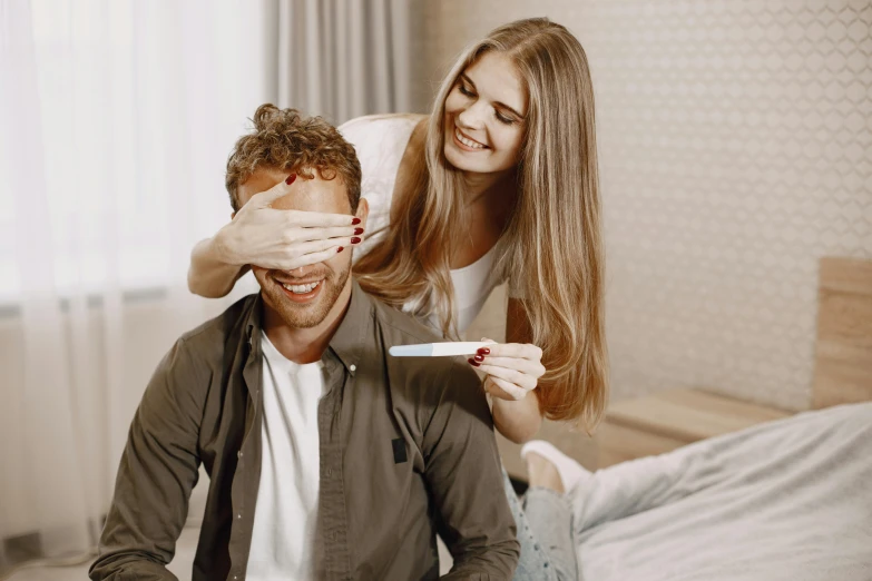 a young woman putting a paint roller on the head of a young man