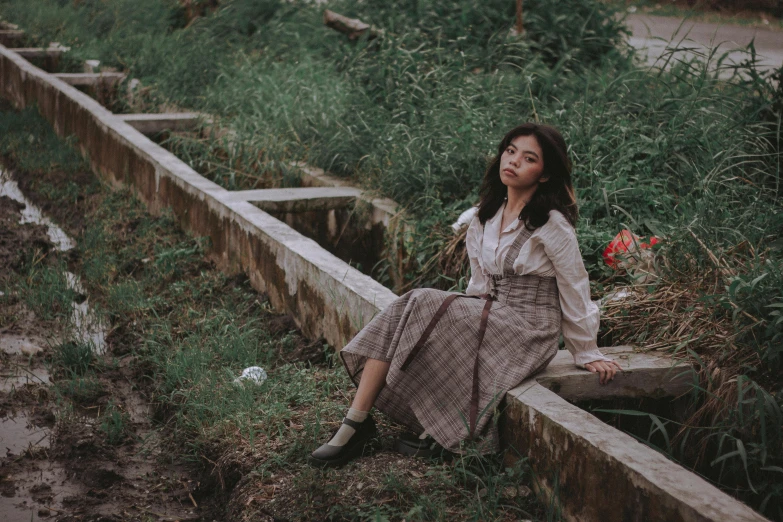 a woman in a dress and white shirt sitting outside