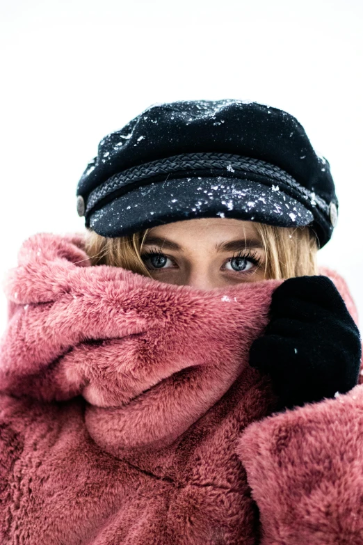 young lady with a pink coat and a hat covering her face