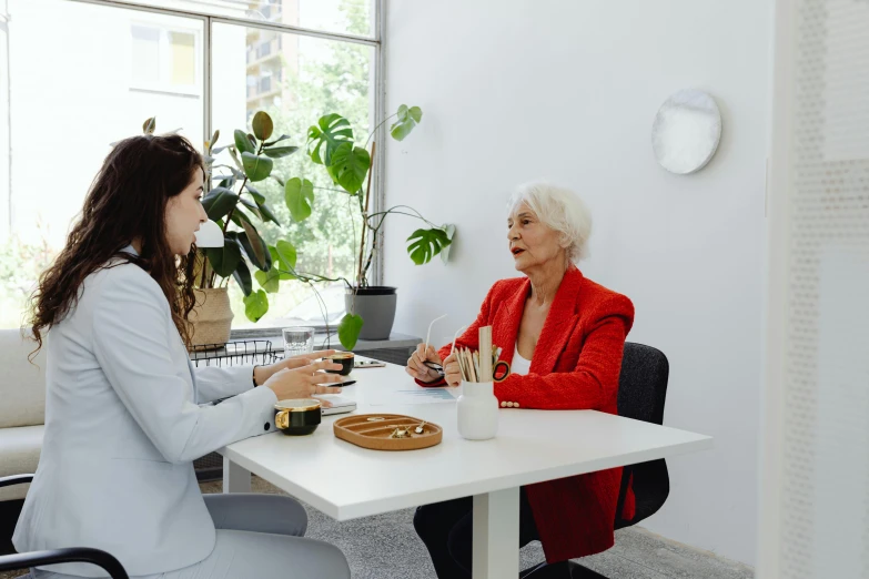 two women sitting at a table talking to each other