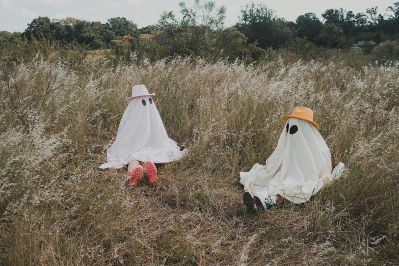 two fake people in dresses sit on the ground