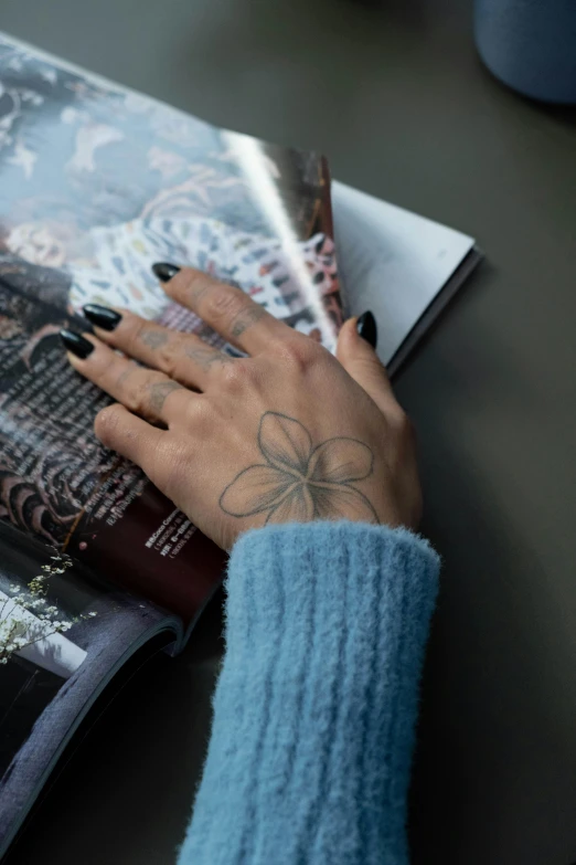 a woman's hand with some nail polish on it sitting next to a magazine