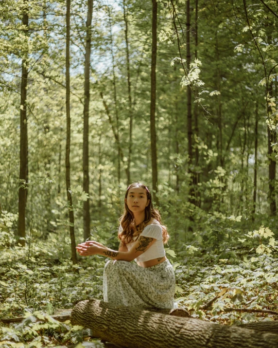 a girl is sitting on a log in the woods