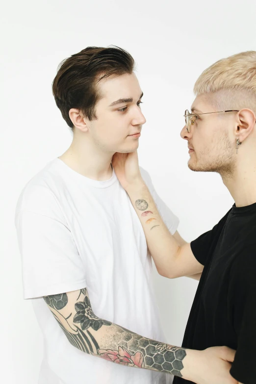 two men with tattooed arms and nose to each other