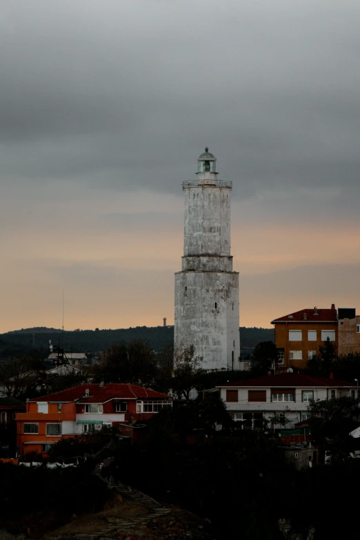 a lighthouse on top of a hill with houses in the background