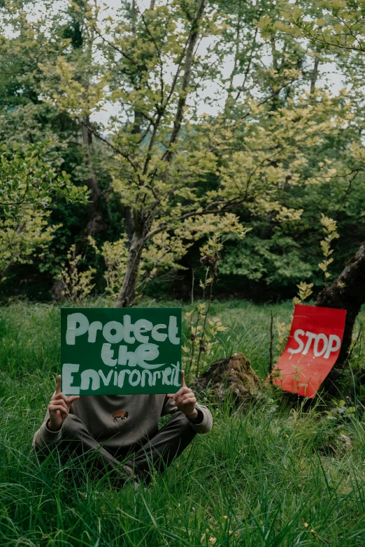 a protest sign in the grass next to a red stop sign