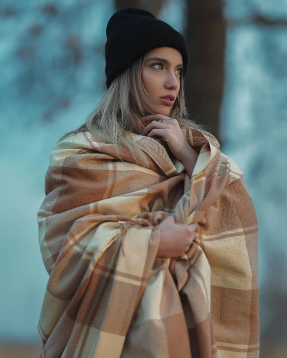 a woman standing with her hand on the other side of a brown and tan striped blanket